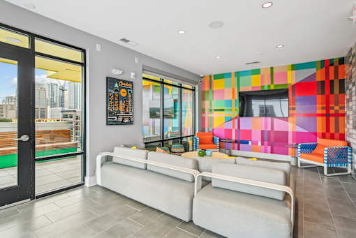 a living room with couches and a television and a colorful wall at Link Apartments® Mint Street, North Carolina