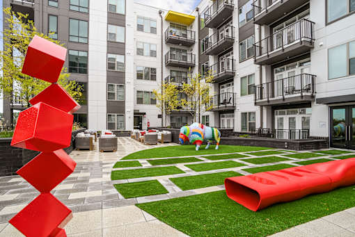 an apartment courtyard with a large red sculpture in front of an apartment building at Link Apartments® Mint Street, Charlotte, North Carolina
