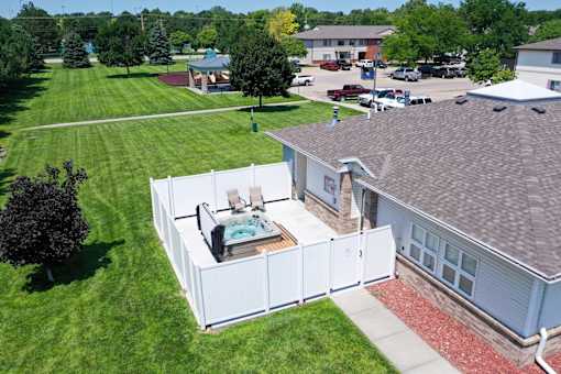 A hot tub is on a deck outside a house.