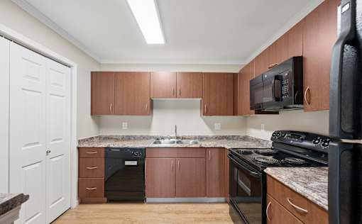 A kitchen with brown cabinets and black appliances.