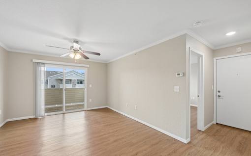 A room with a ceiling fan and sliding glass doors.