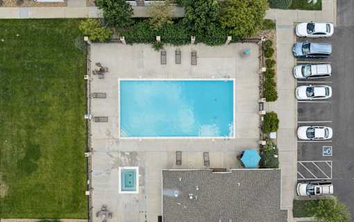 An aerial view of a swimming pool surrounded by a parking lot.