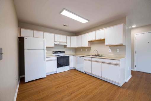 A kitchen with white cabinets and a wooden floor.