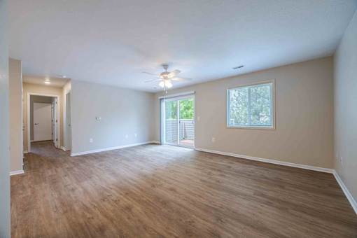 A spacious room with wooden flooring and a ceiling fan.