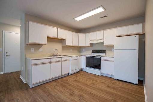 A kitchen with white cabinets and a wooden floor.