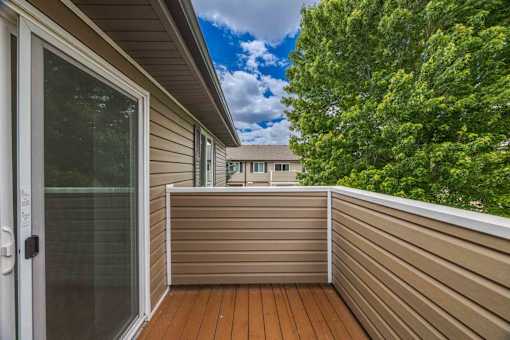 A balcony with a glass door and a wooden floor.