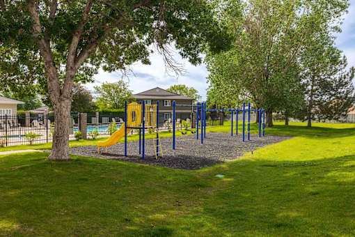 A playground with a yellow slide and blue swings.