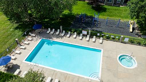 An aerial view of a swimming pool surrounded by lounge chairs and trees.