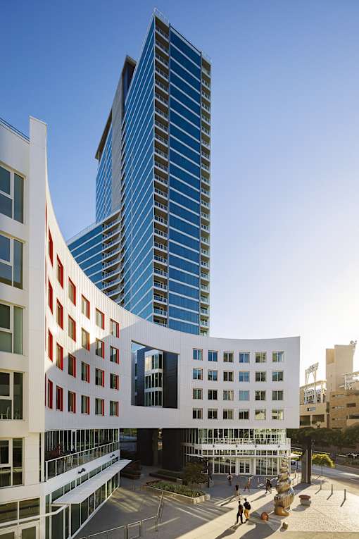 A modern building with a curved white section in front of a tall blue building.
