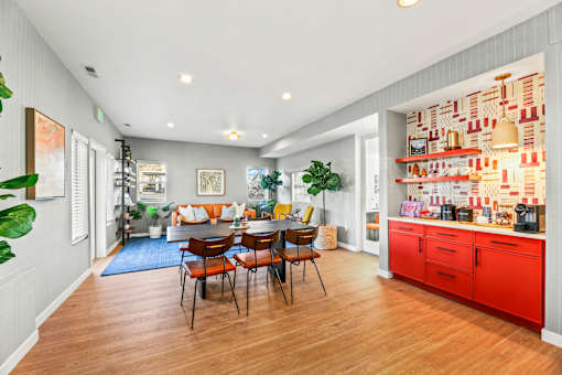 A kitchen with red cabinets and a dining table with chairs.