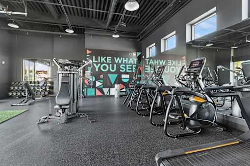 A gym with a row of treadmills and a motivational sign on the wall.