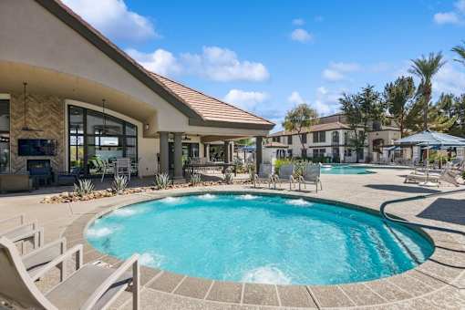 a pool with chairs and umbrellas in front of a building