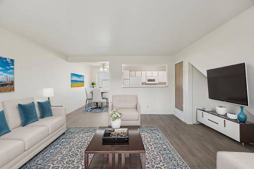 A living room with a white couch, a coffee table, and a television.