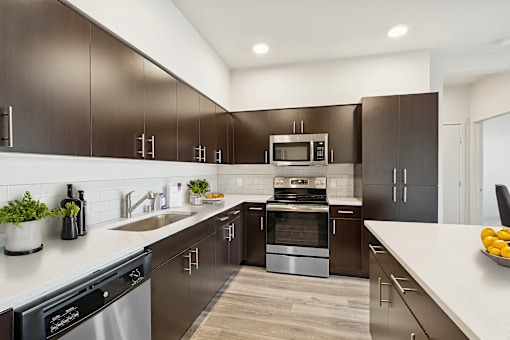 A modern kitchen with dark brown cabinets and stainless steel appliances.