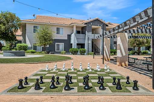 A chess board with black and white pieces in front of a building.