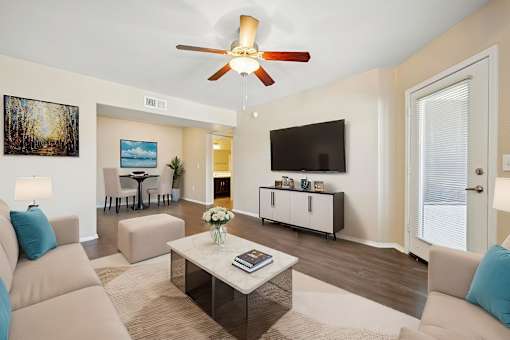A living room with a beige couch, a coffee table, and a ceiling fan.