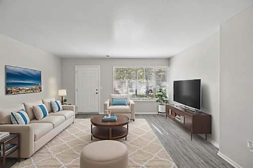 A living room with a couch, chair, ottoman, and television.
