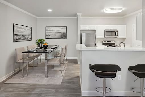 A kitchen with a bar stool and a dining table.