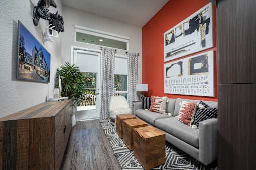 a living room with an orange accent wall and a gray couch