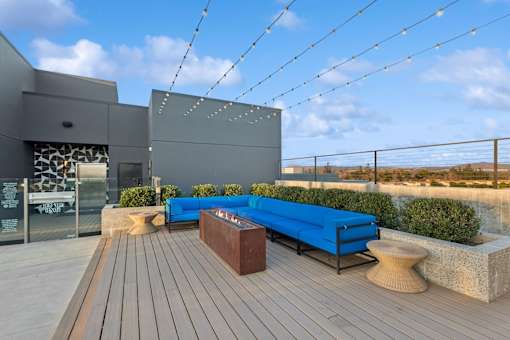 A modern outdoor seating area with a blue bench and wooden deck.