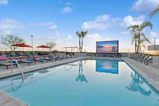 A large screen is mounted on a wall above a swimming pool.
