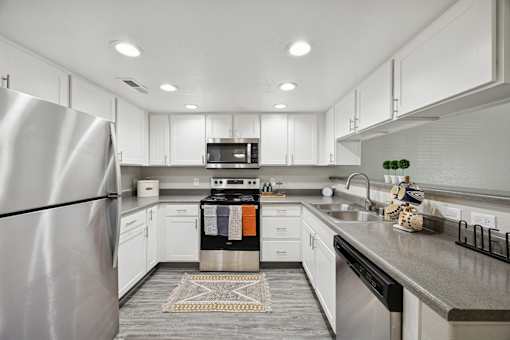 A modern kitchen with a stainless steel refrigerator and white cabinets.
