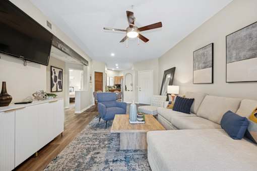 A living room with a white couch and a blue rug.