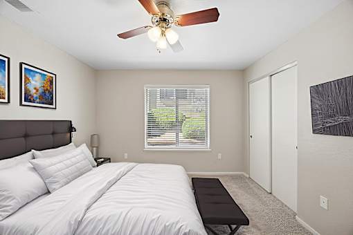 A bedroom with a large bed and a ceiling fan.