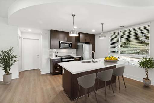 A modern kitchen with a curved island and bar stools.