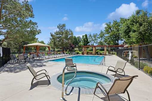 A pool surrounded by chairs and trees.