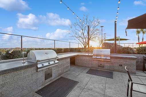 A rooftop patio with a grill and a table.