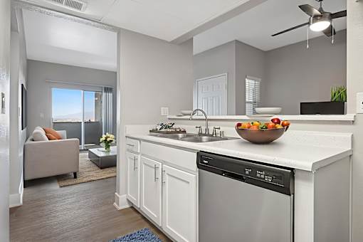 A modern kitchen with a large island and a bowl of fruit on the counter.