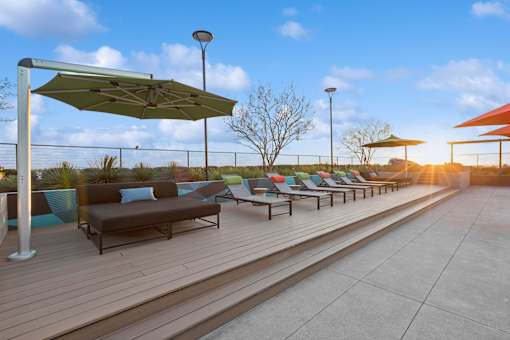 A row of lounge chairs and umbrellas are set up on a wooden deck.