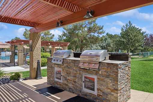 A covered picnic area with a grill and a sign.