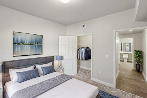 A bedroom with a large bed and a painting on the wall.