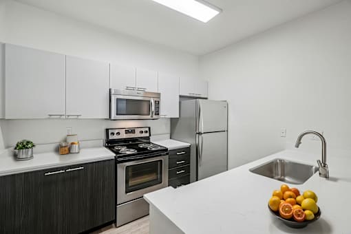 A kitchen with a stove, oven, refrigerator, and sink.