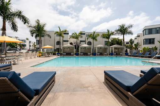 A pool surrounded by lounge chairs and umbrellas.