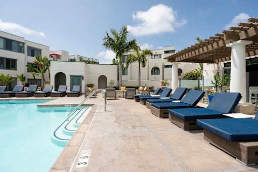 A pool with lounge chairs and a building in the background.