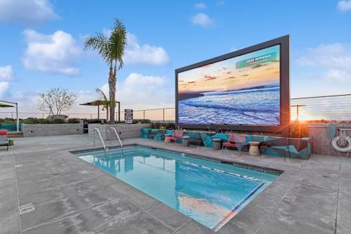 A large screen TV is mounted on a wall above a swimming pool.