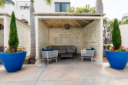A patio with a white pergola and blue planters.