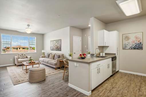 A well-lit, spacious living room with a kitchen area in the background.
