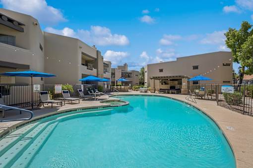 A large swimming pool in front of a building with a fence around it.