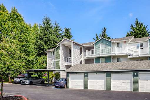 A row of townhouses with garages and cars parked in front.