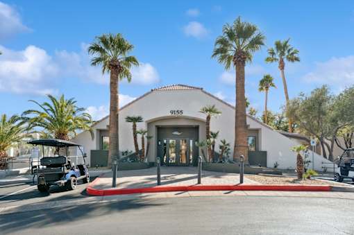 A white building with palm trees in front of it.