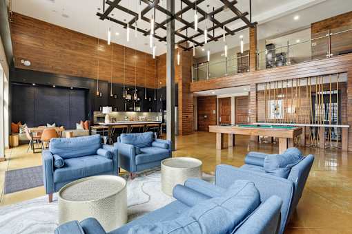 A modern living room with blue couches and a pool table.