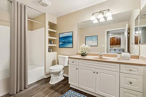 A bathroom with a white toilet, sink, and cabinets.