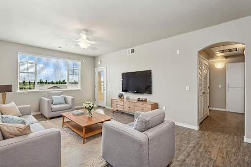 A living room with a grey couch, a wooden coffee table, and a flat screen TV.