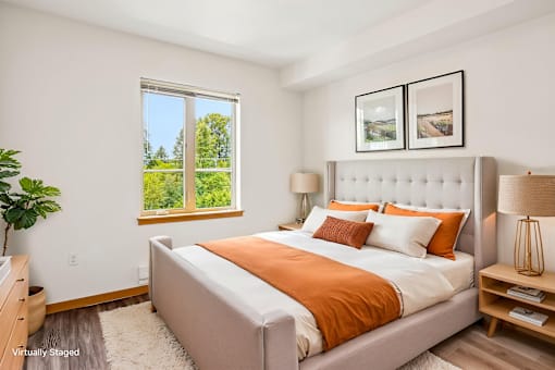 A bedroom with a large bed and a window overlooking a green landscape.