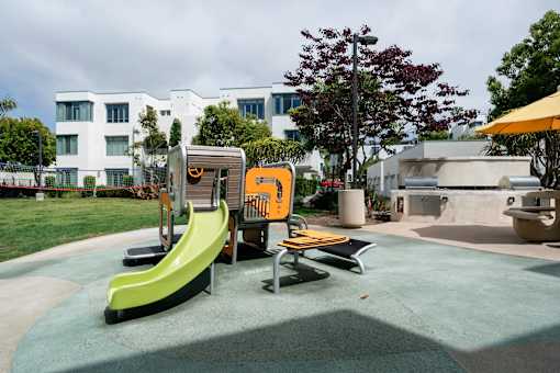 A playground with a yellow slide and a green slide.