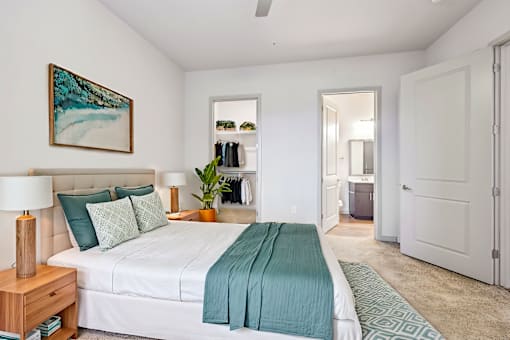 A bedroom with a large bed and a painting on the wall.